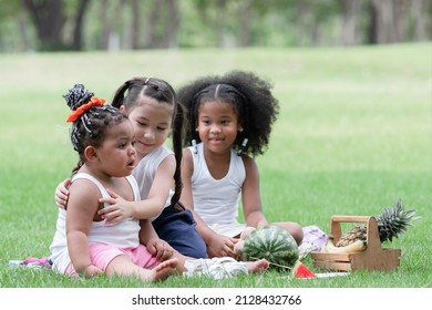 Little African And Caucasian Kids Picnic And Playing In The Park. Little Cute Girl Hugging And Consoling Her Crying Friend. Friendship Of Diverse Ethnicity Children