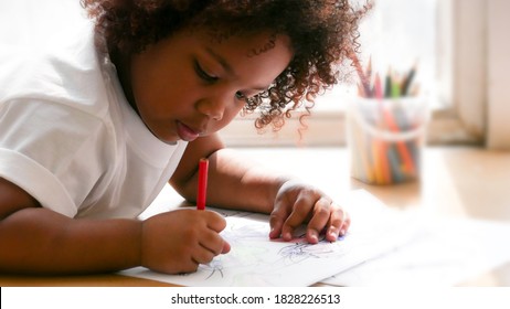 Little African girl painting and drawing on paper. Preschool girl lying writing on floor. - Shutterstock ID 1828226513