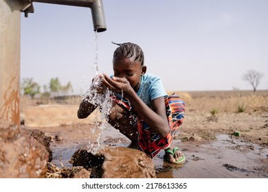 Little African girl splashing herself with copious amounts of clean water at a freshwater well located in an Sub saharan arid region - Shutterstock ID 2178613365