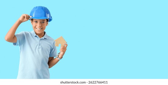 Little African-American architect with house model on light blue background with space for text