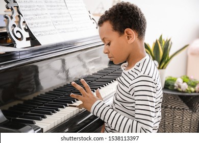 Little African-American boy playing grand piano at home - Powered by Shutterstock