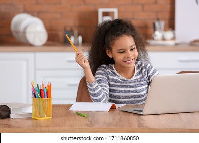 Little African-American girl doing homework in kitchen - Powered by Shutterstock