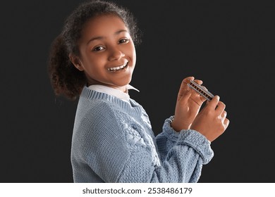 Little African-American girl with harmonica on dark background - Powered by Shutterstock