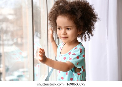 Little African-American Girl Near Window. Child In Danger