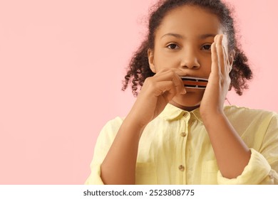 Little African-American girl playing harmonica on pink background, closeup - Powered by Shutterstock