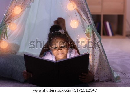 Little African-American girl reading bedtime story in hovel