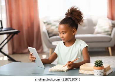 Little African-American girl with tablet computer and notebook at home - Powered by Shutterstock