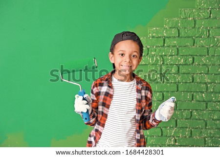 Little African-American painter near color wall