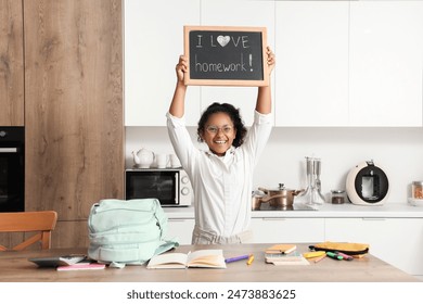 Little African-American schoolgirl holding chalkboard with text I LOVE HOMEWORK in kitchen - Powered by Shutterstock