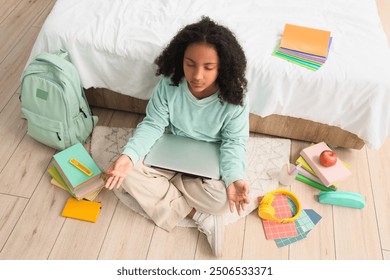 Little African-American schoolgirl with laptop meditating in bedroom - Powered by Shutterstock