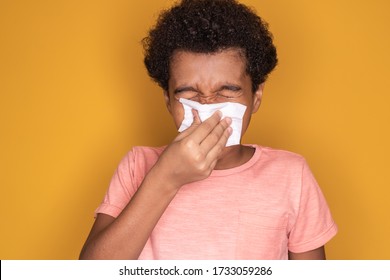 Little afro child boy blow his nose. Sick child with napkin . Allergic kid, flu season. Kid with cold rhinitis, get cold snot nose. virus and infection