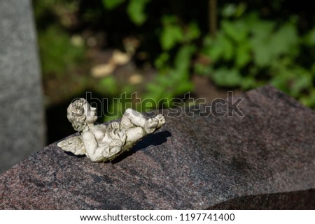 Little angel lies comfortably on a stone