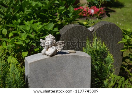 Little angel with wings lies on a marble tombstone