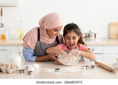 Little Arab Girl Kneading Dough While Baking With Muslim Mom In Kitchen, Caring Islamic Lady In Hijab Teaching Her Cute Female Child Cooking, Mom And Kid Having Fun Together At Home, Free Space