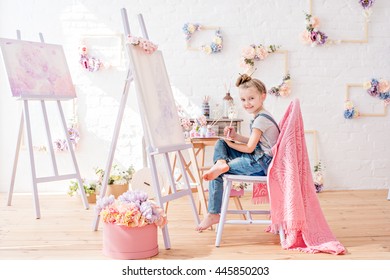 Little Artist In Denim Overalls Painting Brushes On The Easel In Her Studio