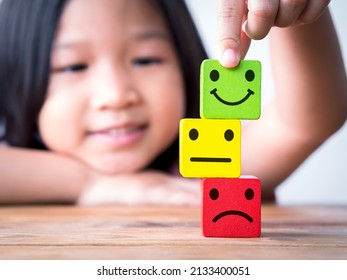 Little Asia Child Girl Putting Happy Smiley Face On Top Of Neutral And Sad Or Unhappy Face Icon On Wood Cube. Concept Of Happy Children, Kid, Family, Childrens Day.