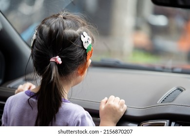 Little Asian 3-5 years old girl is looking outside through car window mirror.