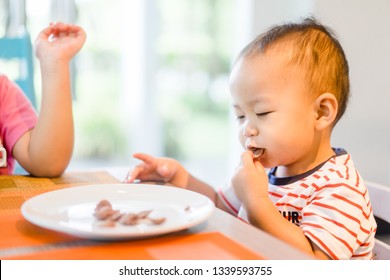 Little asian baby 2 years boy Eating cereal and fries in lunch time with hands at restaurant.Enjoy eating and hungry concept. - Powered by Shutterstock