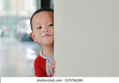 Little Asian Baby Boy Hide Behind A Corner Room. Small Children Playing Peekaboo Game Indoor.