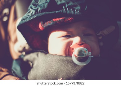 Little Asian Baby Boy With Pacifier In Baby Carrier. Child Is 6 Months Old.