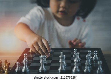 Little Asian Baby Girl Playing Chess.Smart Kid.fashion Children. Little Genius Child. Intelligent Game.Chessboard. Baby Activity Concept.