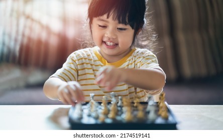 Little Asian Baby Playing Chess In The Living Room At Home.Smart Kid.fashion Children. Little Genius Child. Intelligent Game.Chessboard. Baby Activity Concept.