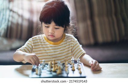 Little Asian Baby Playing Chess In The Living Room At Home.Smart Kid.fashion Children. Little Genius Child. Intelligent Game.Chessboard. Baby Activity Concept.