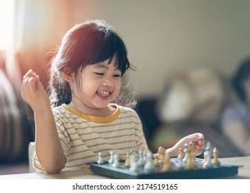 Little Asian Baby Playing Chess In The Living Room At Home.Smart Kid.fashion Children. Little Genius Child. Intelligent Game.Chessboard. Baby Activity Concept.