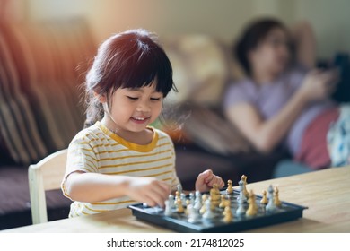 Little Asian Baby Playing Chess In The Living Room At Home.Smart Kid.fashion Children. Little Genius Child. Intelligent Game.Chessboard. Baby Activity Concept.