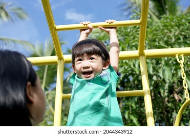 Little Asian Boy Climbing On Monkey Bar At Outdoor Playground