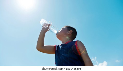 Little Asian Boy Drinking Water Against Blue Sky.