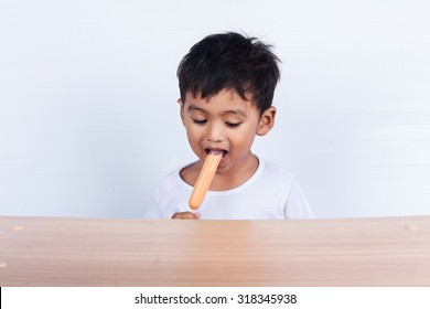 A Little Asian  Boy Eating Sausage On White Background