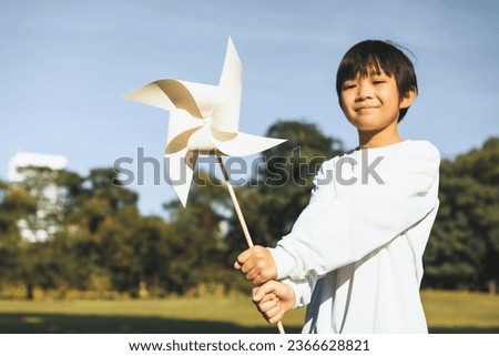 Little asian boy holding windmill or wind turbine mockup model to promote eco clean and renewable energy technology utilization for future generation and sustainable Earth. Gyre