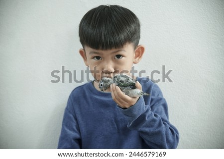 Little asian boy kissing baby parrot isolated on white background 