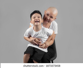 Little Asian Boy Kissing Mother, Young Cancer Patient, On The Cheek. Cancer And Family Support Concept.