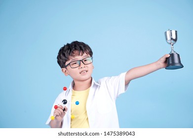 Little Asian Boy Learning Chemical In Science With White Blouse Coat, Isolated On Blue Background