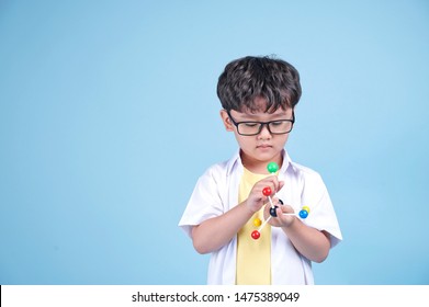 Little Asian Boy Learning Chemical In Science With White Blouse Coat, Isolated On Blue Background