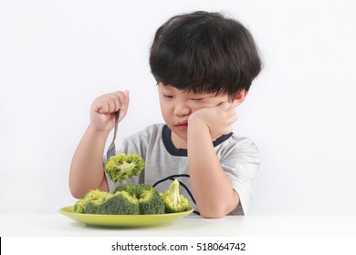 Little Asian boy refuse to eat healthy vegetables.