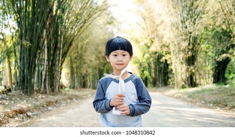 Little Asian Boy Walking With Wind Turbine Toy On Bamboo Tunnel Road : Thailand