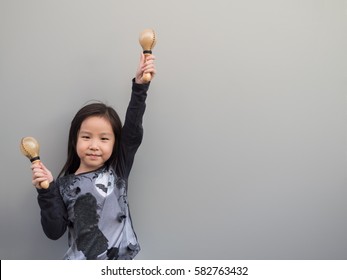 Little Asian Child Play The Maracas, Gray Background