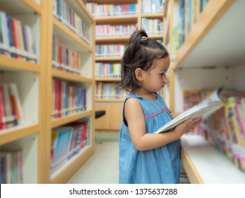 Little Asian Cute Girl 3-4 Years Old Looking A Kid's Book From Bookshelf At The Library. Learning And Education Of Kid.