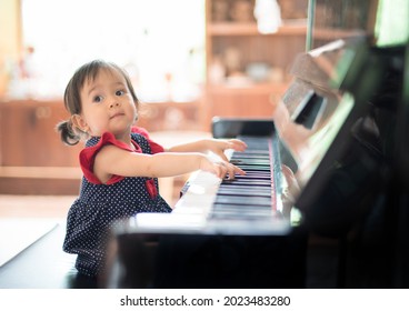 Kleines süßes asiatisches Mädchen beim Klavierspielen