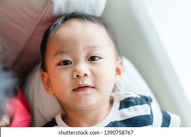 Little Asian Cute Toddler Boy Watching Tv On His Sofa And Looking Up Alone.