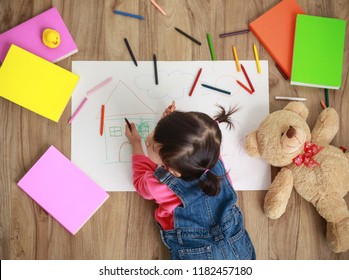 Little Asian girl drawing in paper on floor indoors - Shutterstock ID 1182457180