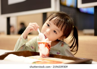 Little Asian Girl Eating Ice Cream At Restaurant. Soft Focus. Copy Space.