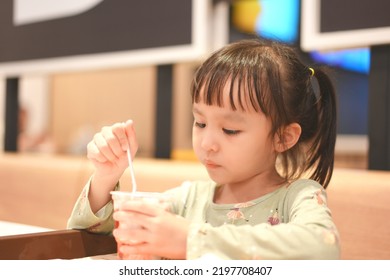 Little Asian Girl Eating Ice Cream At Restaurant. Soft Focus. Copy Space.