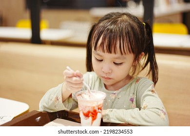 Little Asian Girl Eating Ice Cream At Restaurant. Soft Focus. Copy Space.