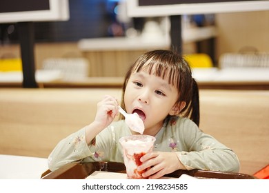 Little Asian Girl Eating Ice Cream At Restaurant. Soft Focus. Copy Space.