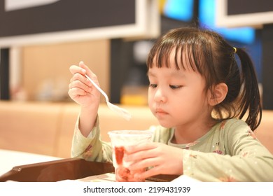 Little Asian Girl Eating Ice Cream At Restaurant. Soft Focus. Copy Space.