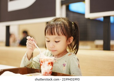 Little Asian Girl Eating Ice Cream At Restaurant. Soft Focus. Copy Space.